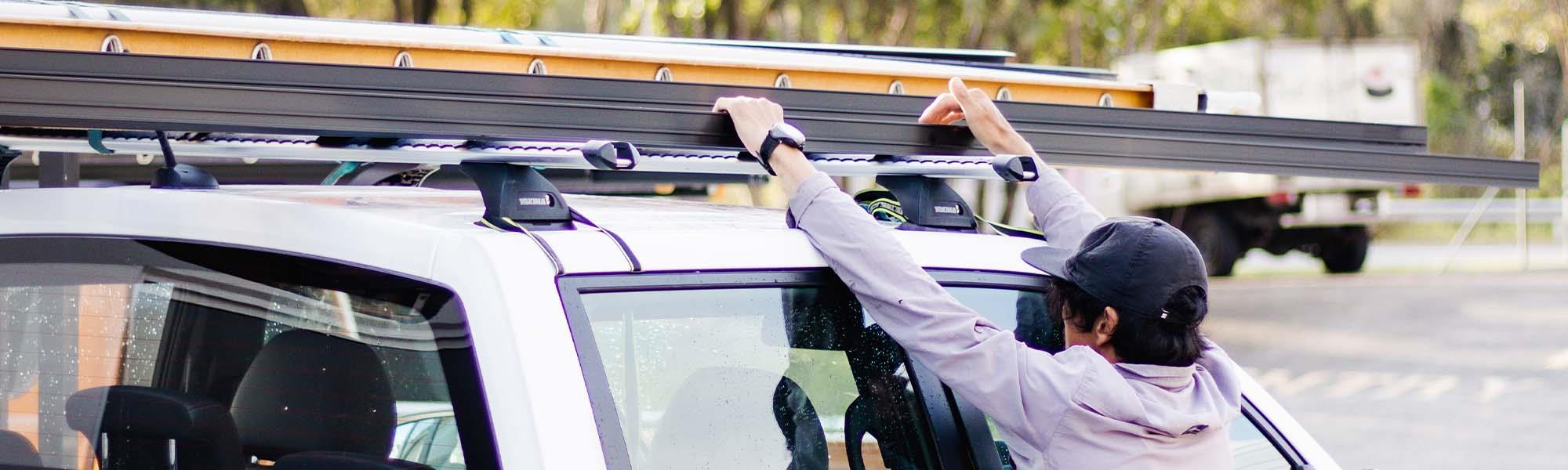 man reaching for ladder on top of a ute