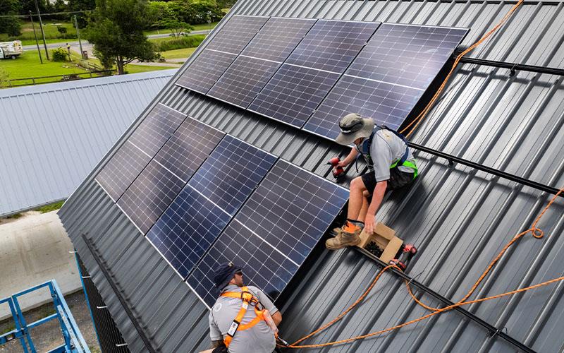 people laying solar panels on shed roof