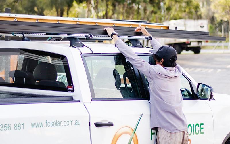 man putting ladder on the roof of car